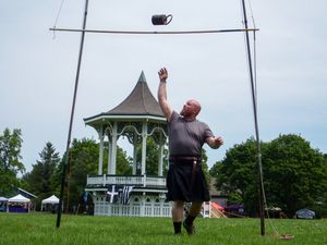 A participant throws a heavy weight over a high bar during Scottish Highland Games.