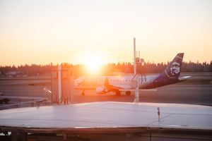 Alaska Airlines plane on tarmac at sunset with golden light illuminating the aircraft at a Pacific Northwest airport.