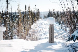 Vince Lombardi Trophy replica standing in deep snow surrounded by snow-covered evergreen trees on a clear winter day.