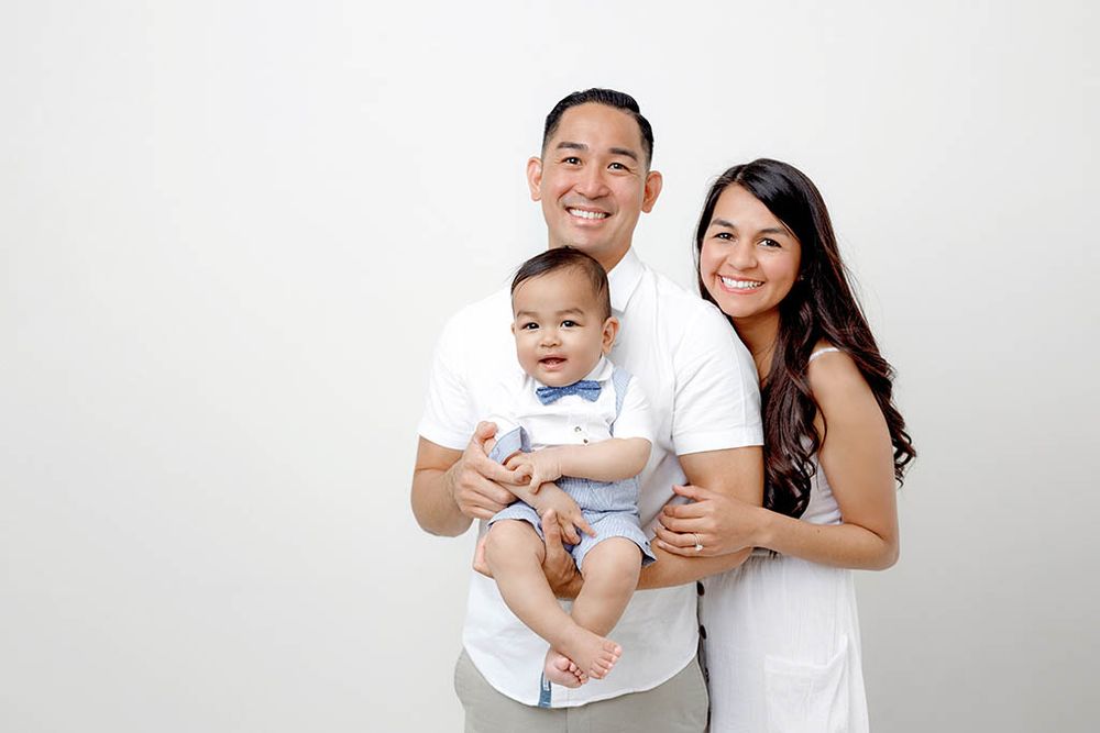 Happy family portrait with parents holding their smiling baby boy for 1st birthday photoshoot near French Valley in Murrieta, CA.