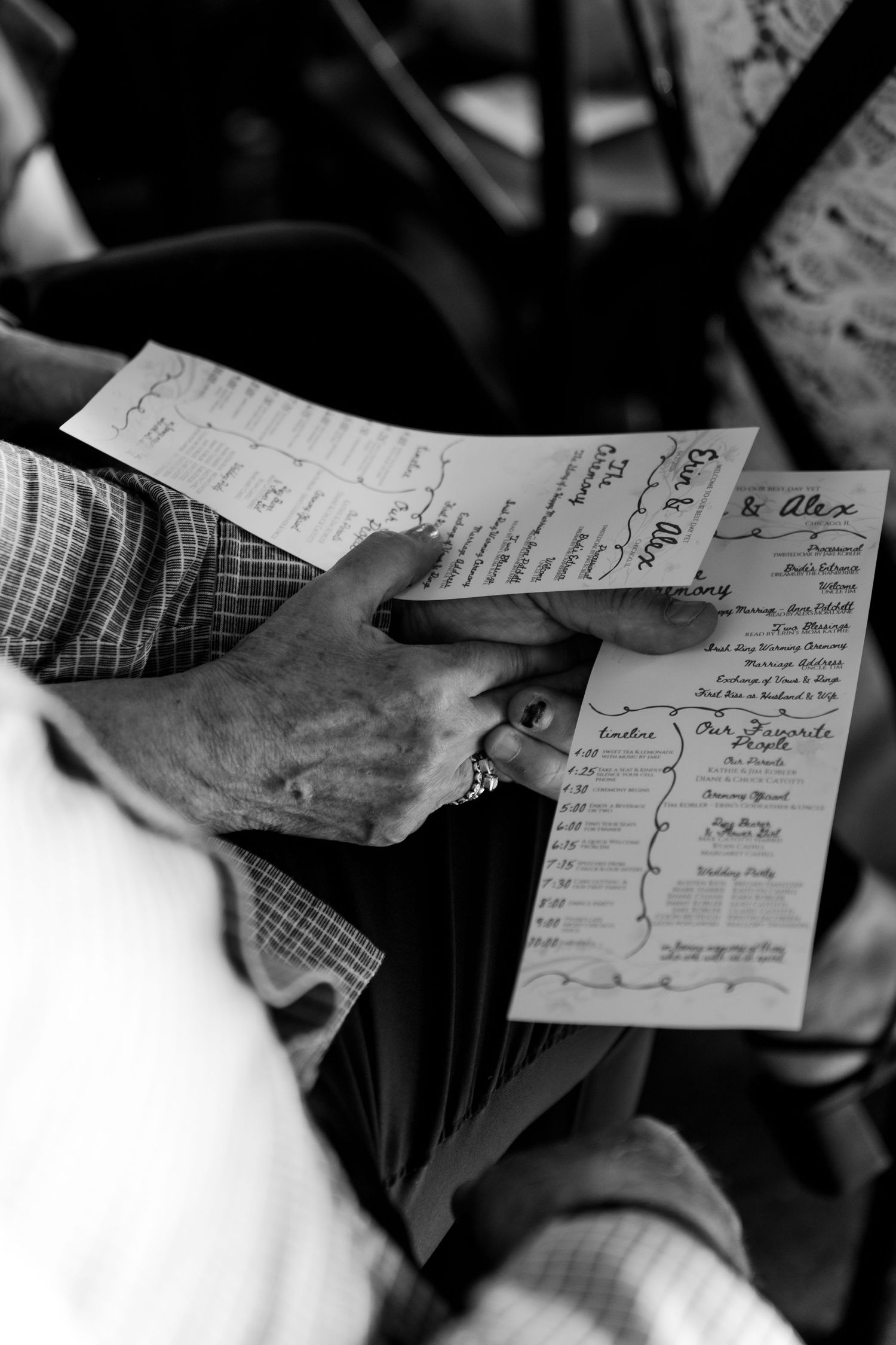 Elderly hands holding a wedding program in black and white photography at a ceremony.
