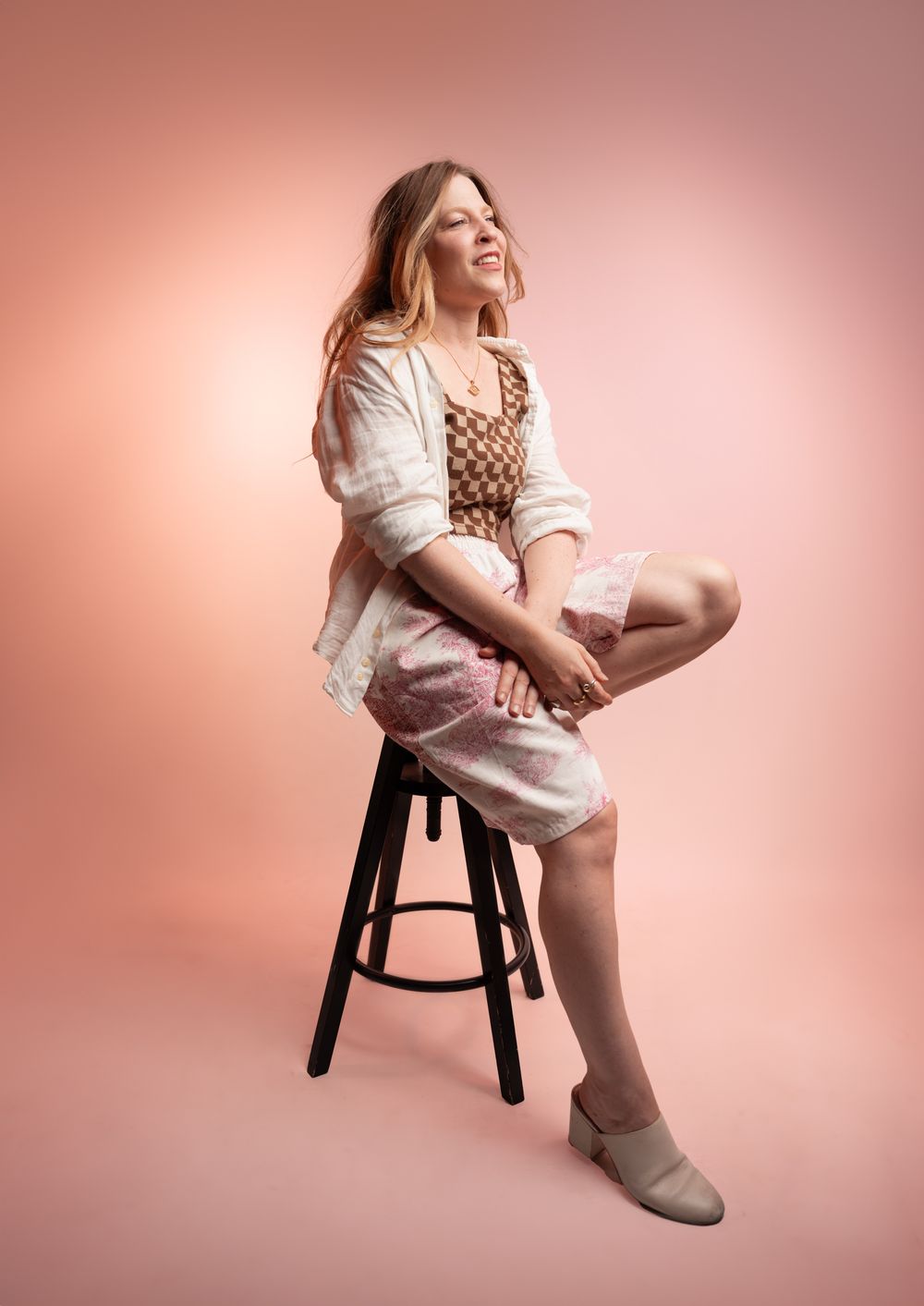 Warm, atmospheric studio portrait of a woman in a pink dress; capturing the golden hour light of Tuscany in a professional setting.