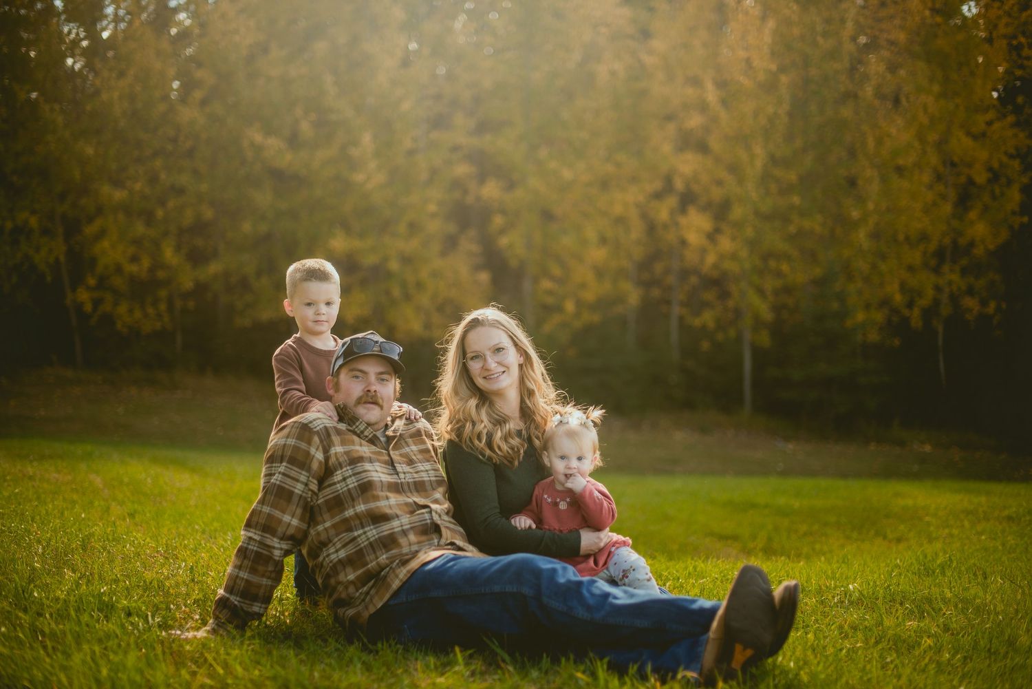 Children in winter coats embrace a floral-dressed pregnant belly while standing outdoors on frosty ground.