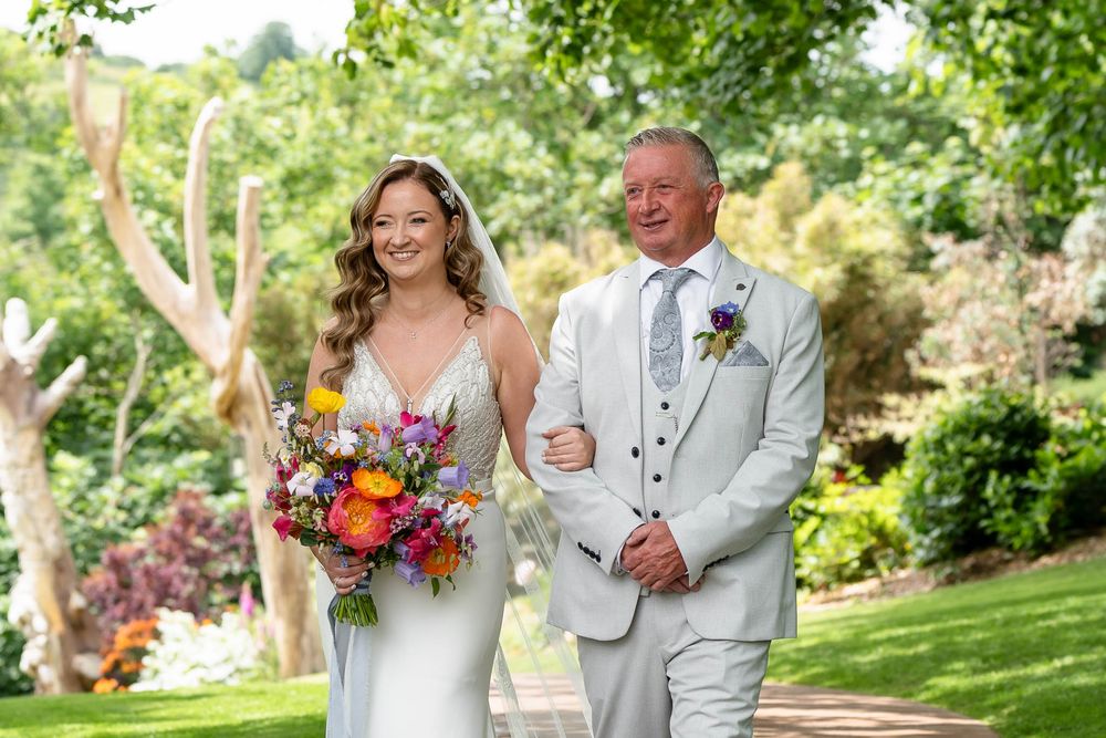 Bride and father walking to the ceremony for her coastal Devon Wedding at Watermouth Cove Weddings