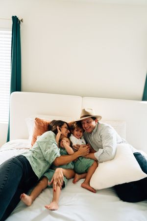 Family relaxing together on a white couch with teal curtains in the background.