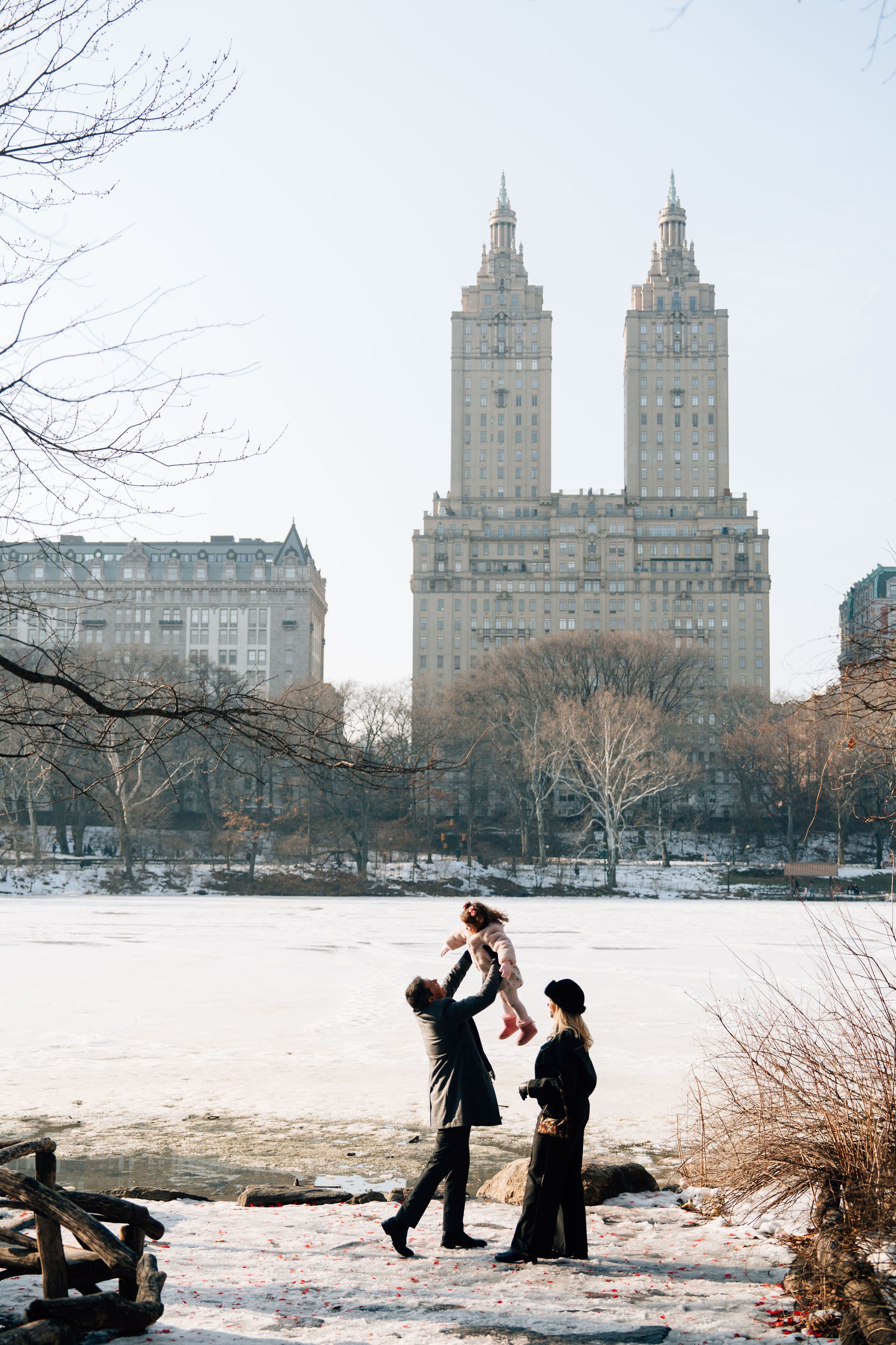 Two people enjoy a snowy winter day in Central Park with the iconic El Dorado building towers in the background.