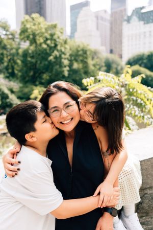 A joyful family moment captured in Central Park with New York City buildings visible in the background.