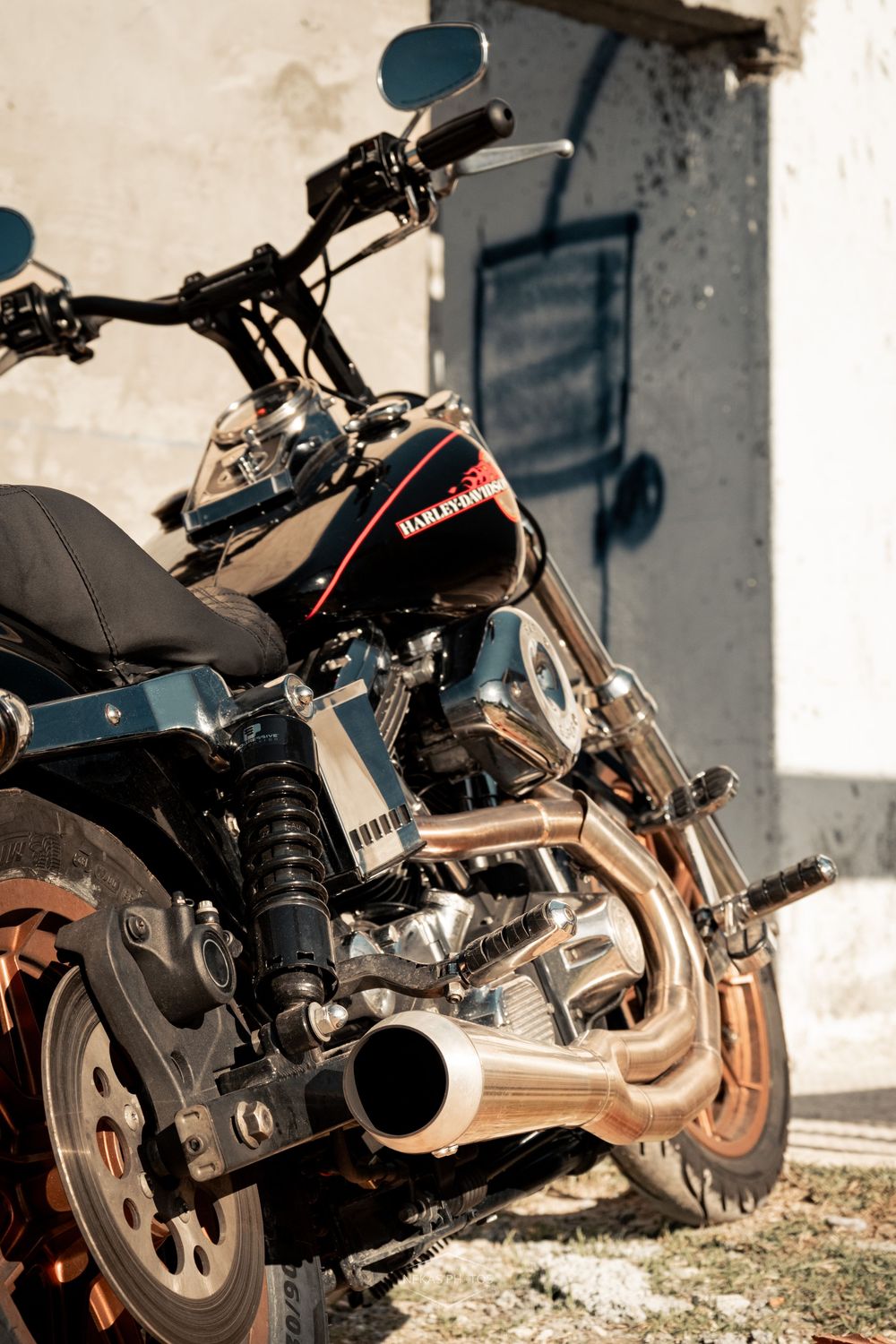 Harley-Davidson motorcycle parked outdoors, showcasing chrome exhaust pipes, black fuel tank, and classic V-twin engine details.