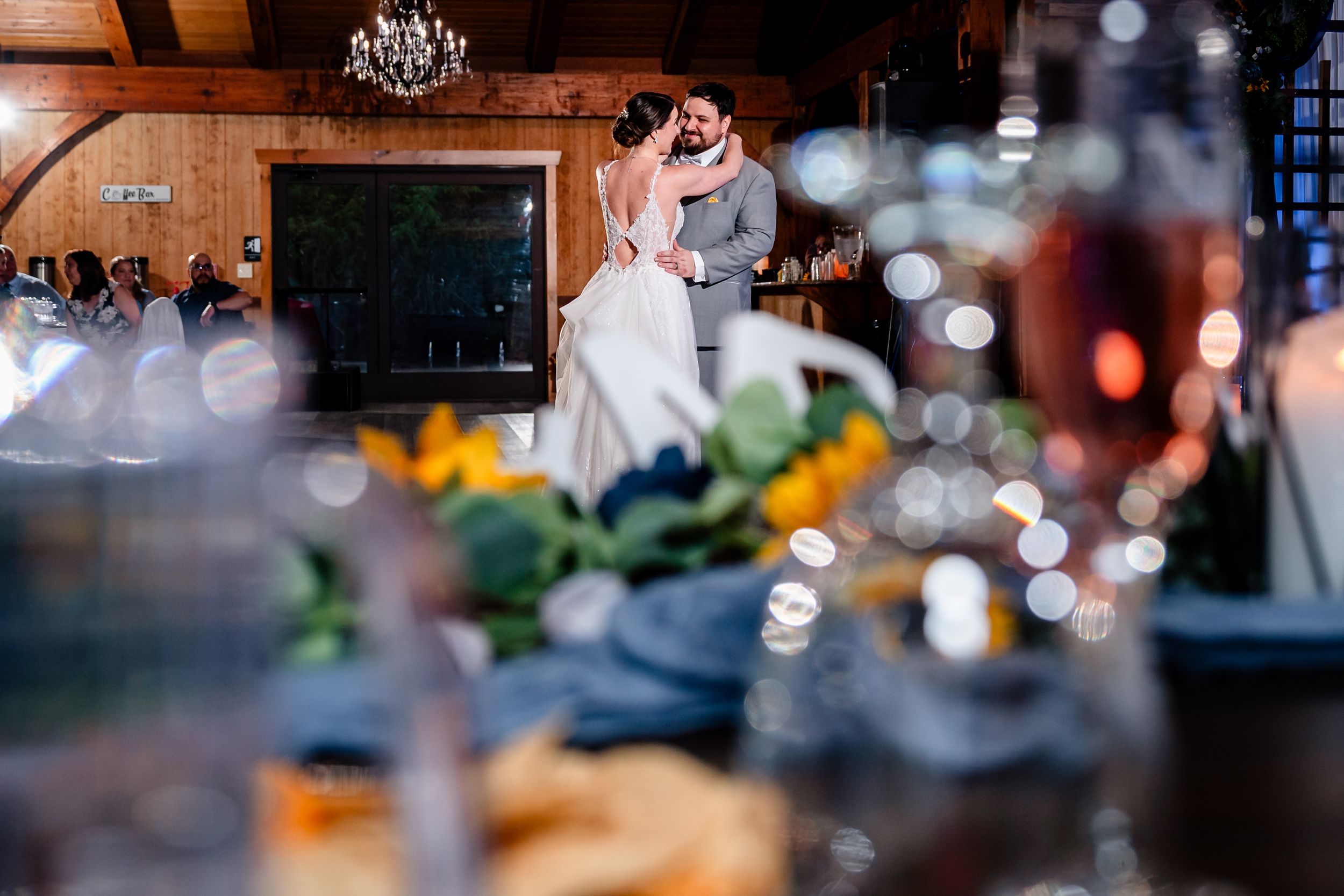 Bride and groom share first dance in warmly lit rustic wedding reception venue.