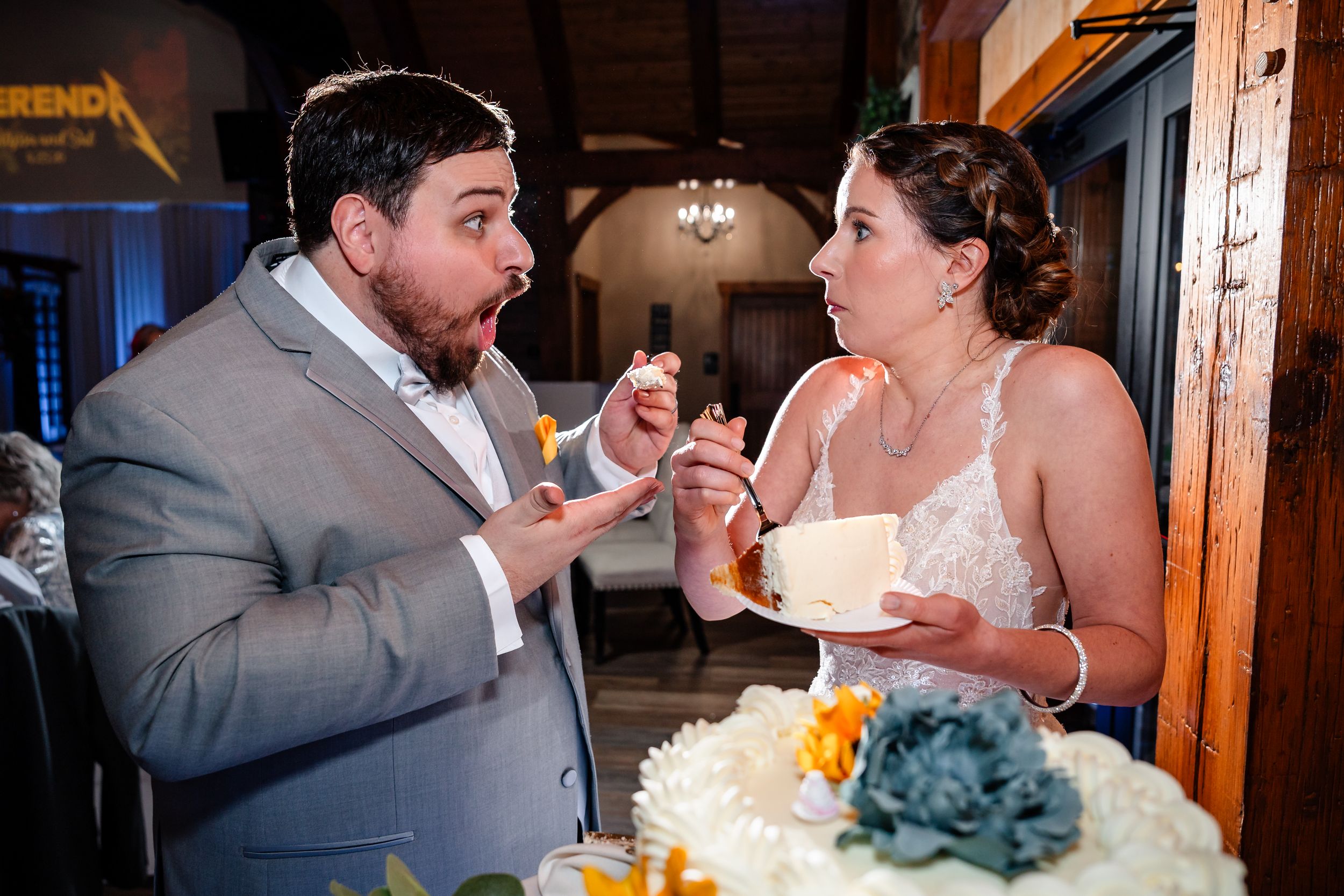 Bride and groom share a joyful moment cutting their wedding cake at their reception.