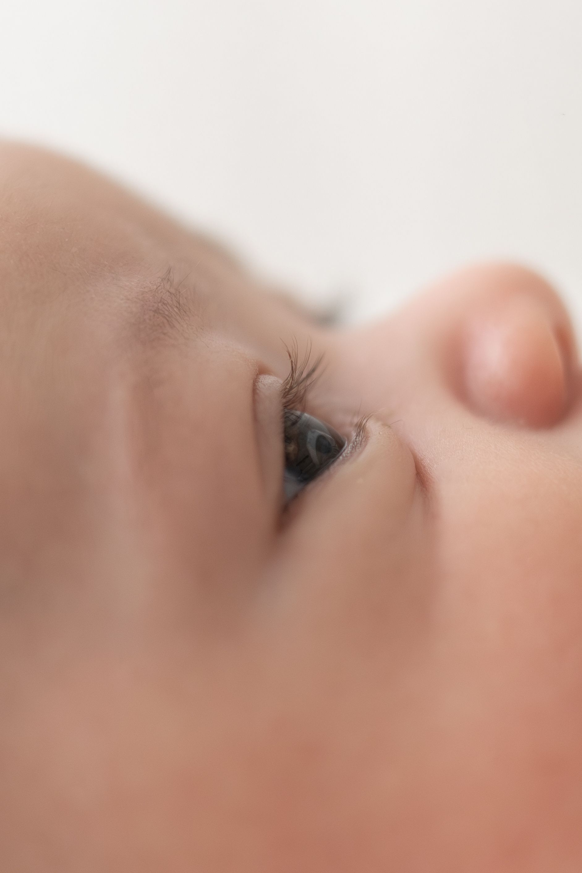 Close-up of a newborn baby's blue eye and delicate eyelashes against soft skin natural older newborn baby photography Nottingham