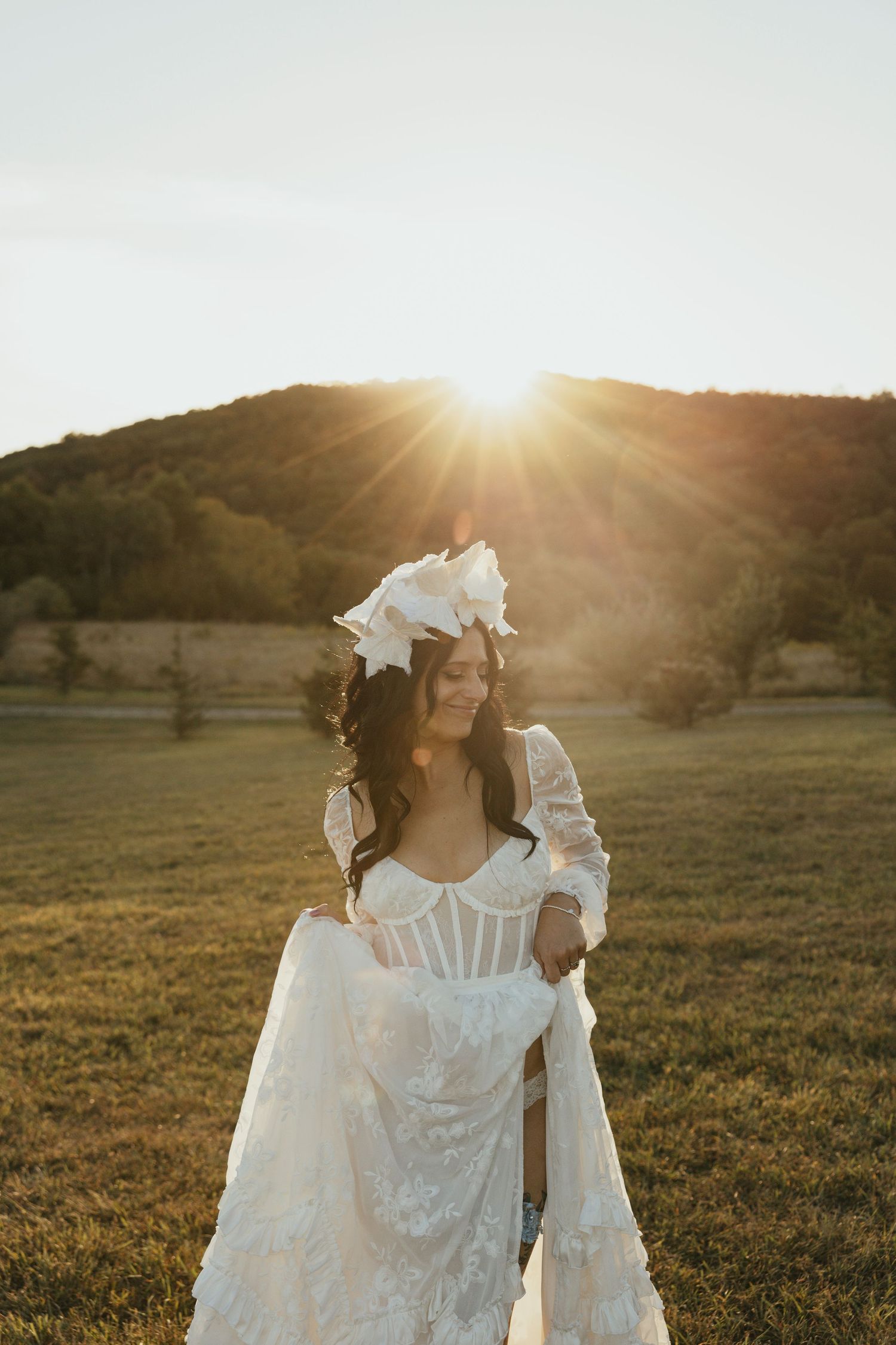 Bride and groom walking on golf course at golden hour sunset, she in white gown, he in black tuxedo.