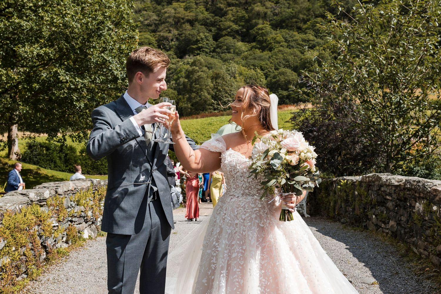 Bride and groom laughing joyfully during outdoor wedding ceremony with guests seated in background.