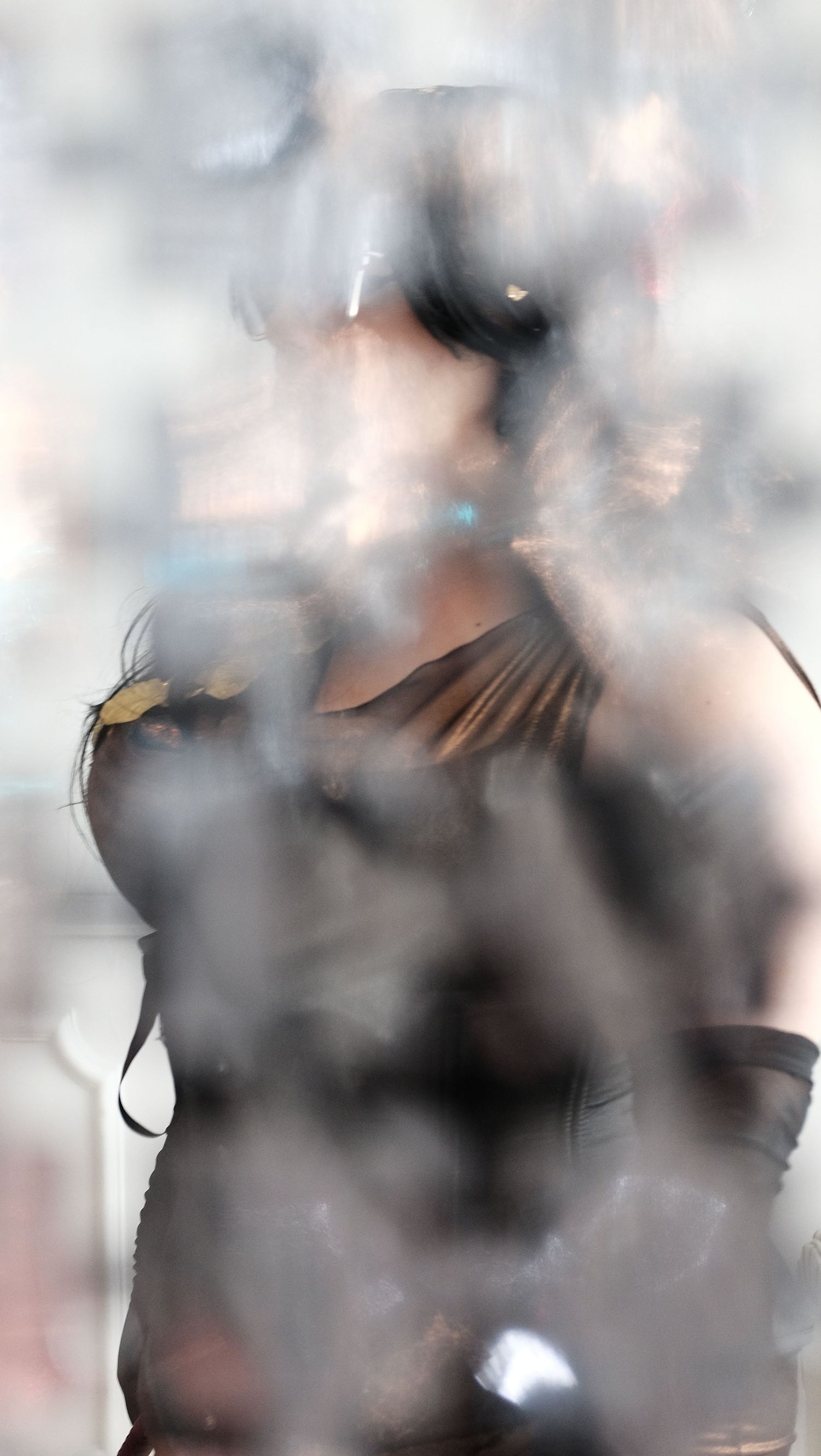 Blurred artistic photo of a woman in dark costume with goggles, surrounded by smoke or fog effects.
