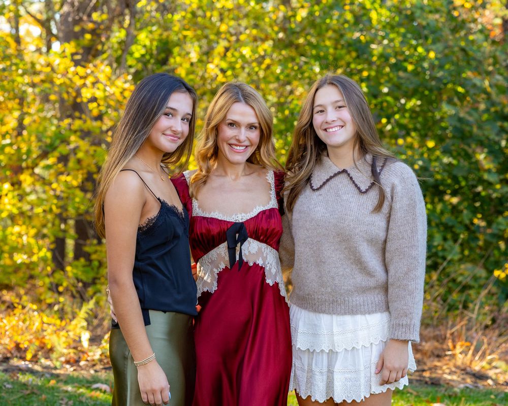 Mother & daughters pose together outdoors among colorful autumn foliage in a warm family portrait in Concord, MA.