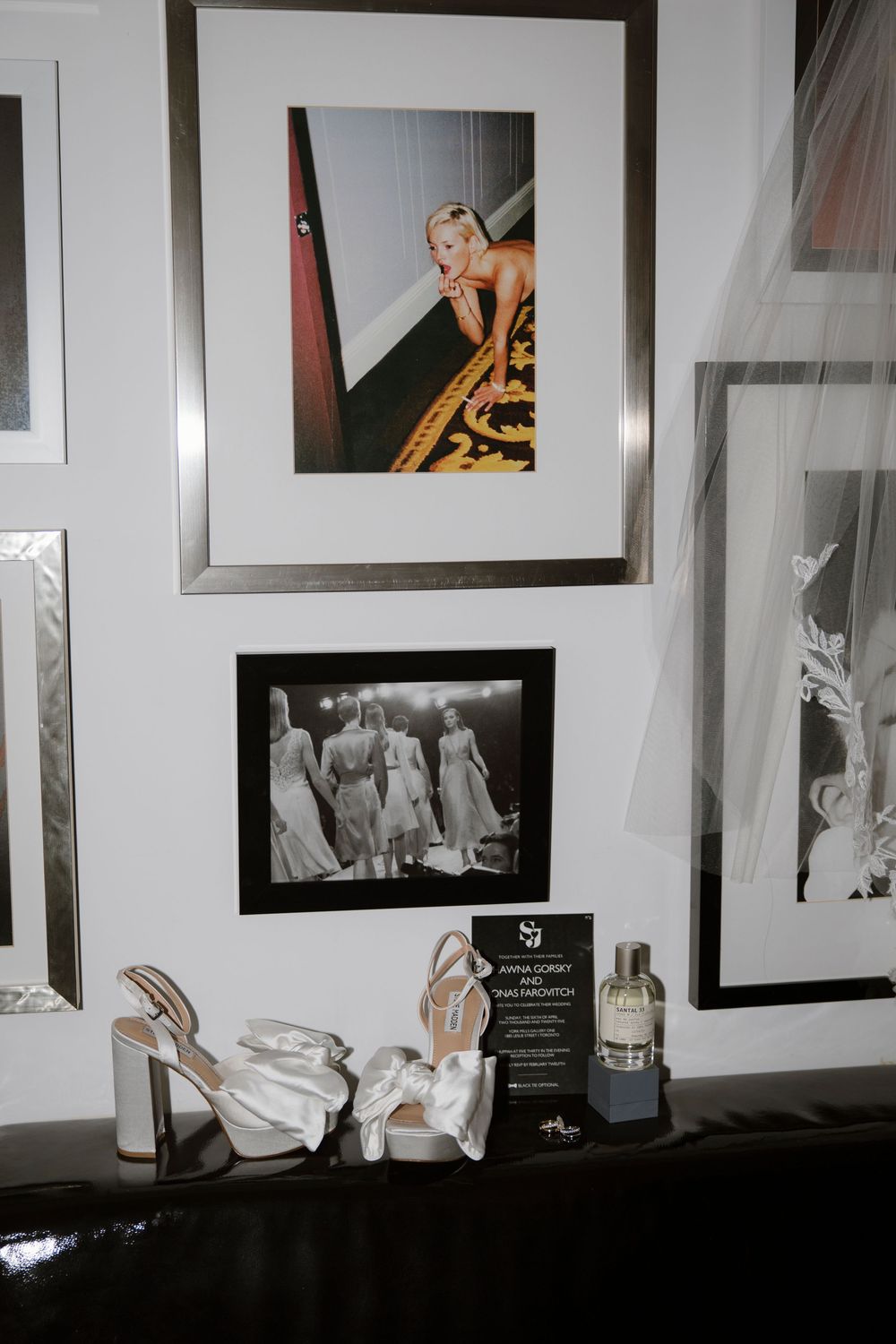 A wall gallery display with framed photos and white high-heeled shoes displayed beneath.