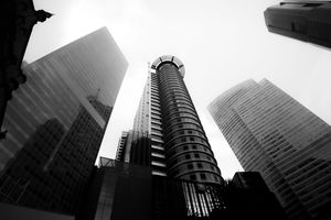 Low angle view of modern skyscrapers against bright sky in black and white.