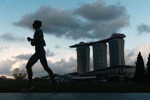 Silhouettes of people against a dramatic cloudy sunset sky with city buildings in background.