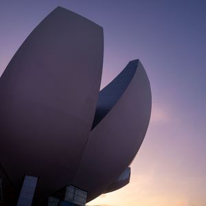 Abstract architectural shapes silhouetted against purple sunset sky.