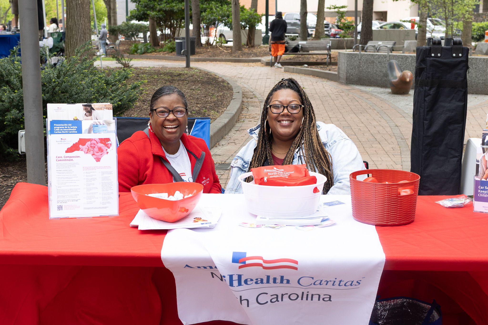 Healthcare volunteers staff information table with materials and supplies at community outreach event.