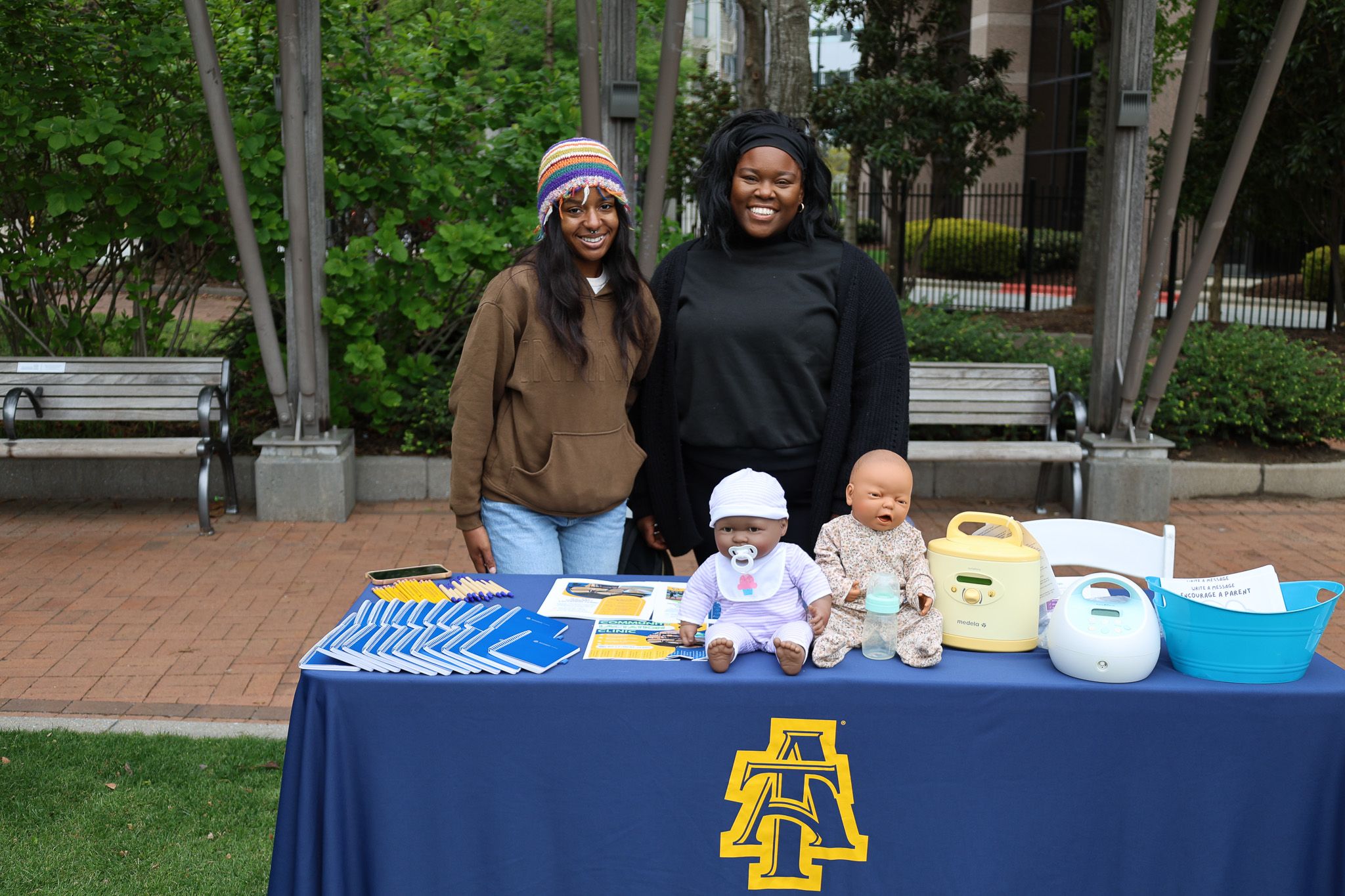 Table setup at outdoor community event with school merchandise and display items.