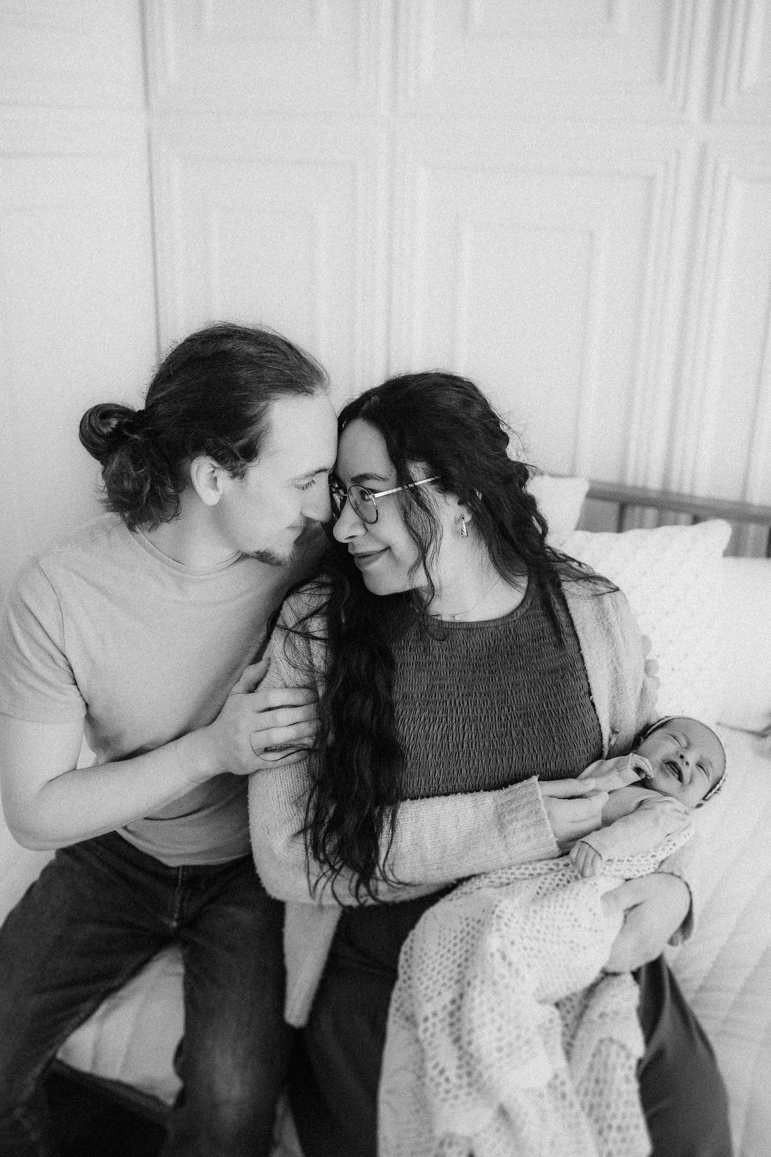A tender black and white photograph of a couple sharing an intimate moment while relaxing together on a couch.