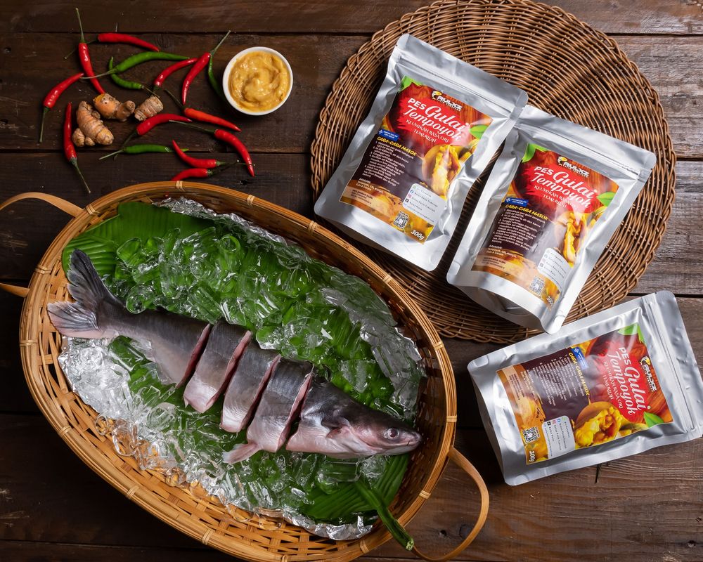 Fresh seafood and spices displayed in woven basket with chili peppers on wooden background.