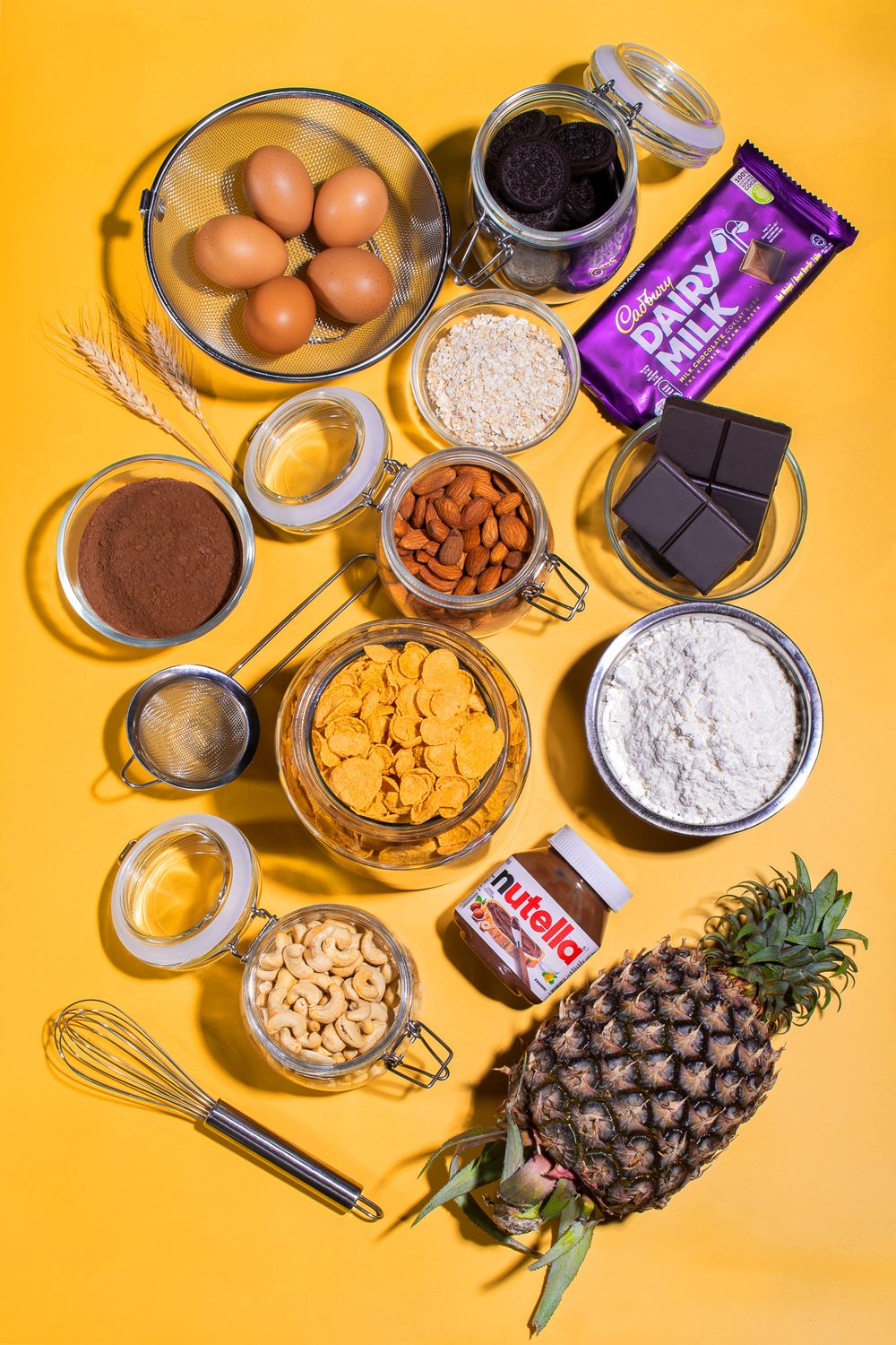 Baking ingredients including chocolate, eggs, and nuts arranged on a bright orange background.