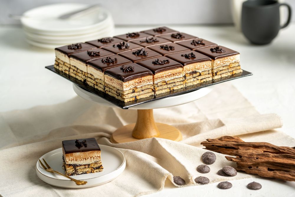 Layered chocolate wafer cake with cream filling on white marble surface.
