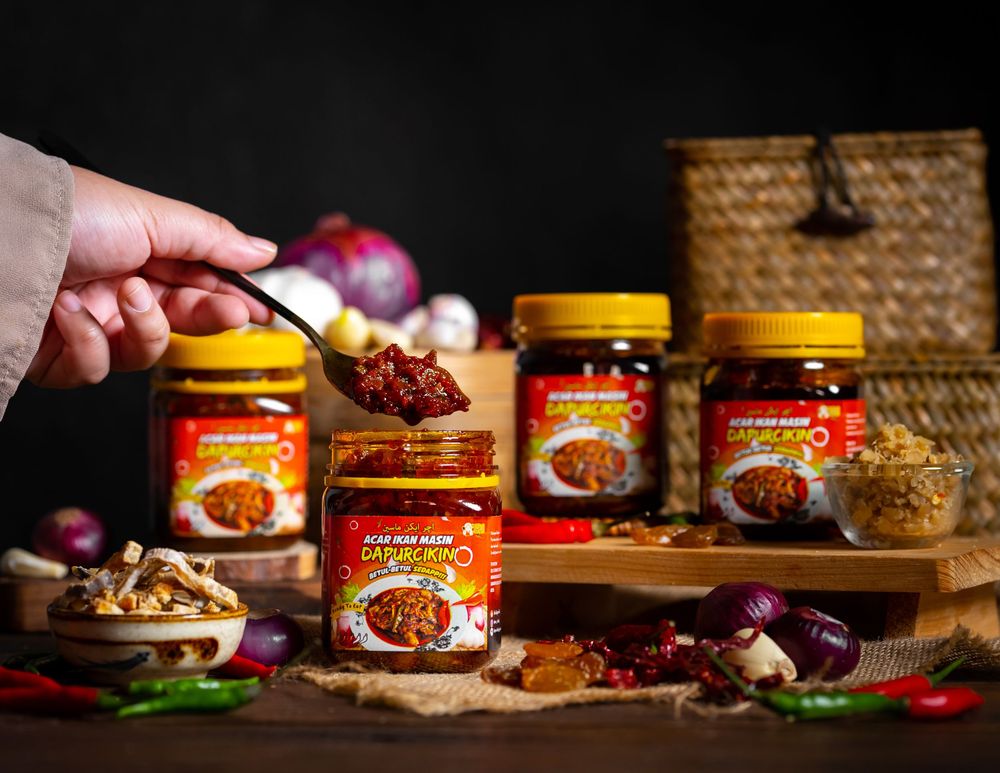 Spicy Asian chili sauce jars displayed with fresh ingredients and garnishes on rustic wooden background.
