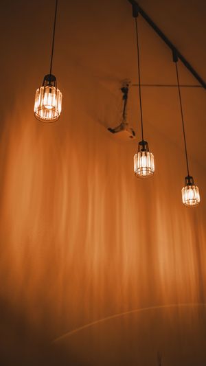 Three vintage-style pendant lights hanging against a warm orange wall create a cozy, atmospheric ambiance.