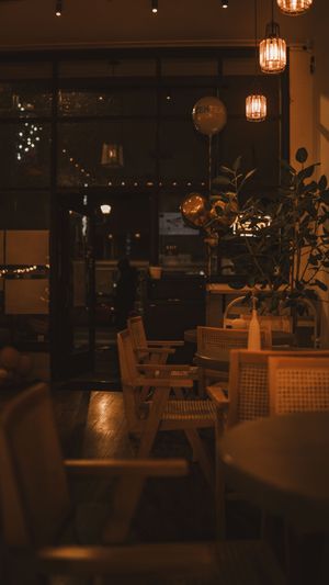 Cozy restaurant interior with warm lighting, wooden chairs, and pendant lamps creating an atmospheric evening ambiance.
