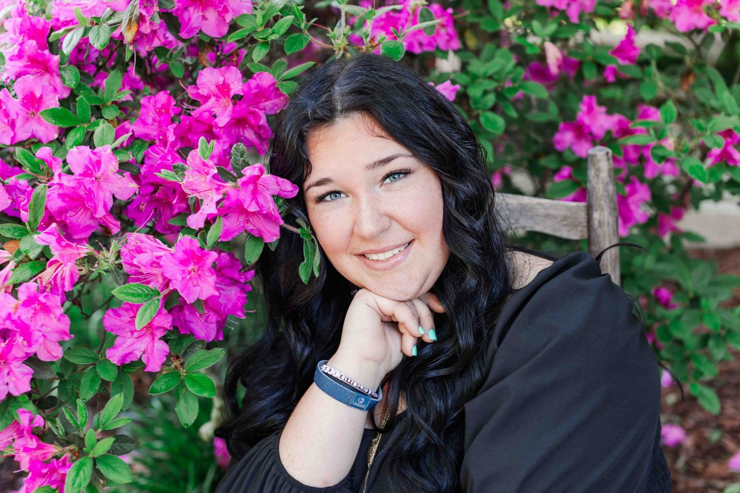 A person with dark hair poses beside vibrant pink bougainvillea flowers in an outdoor portrait session.