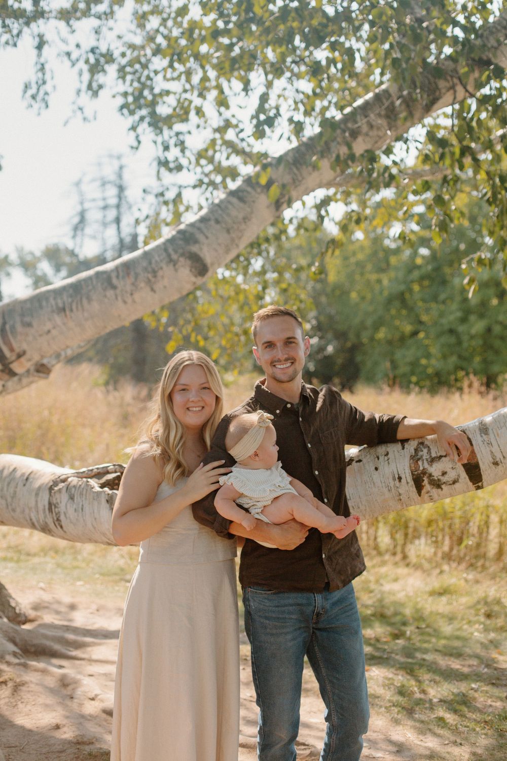 A family of three leaning against a tree during their Grand Rapids family.