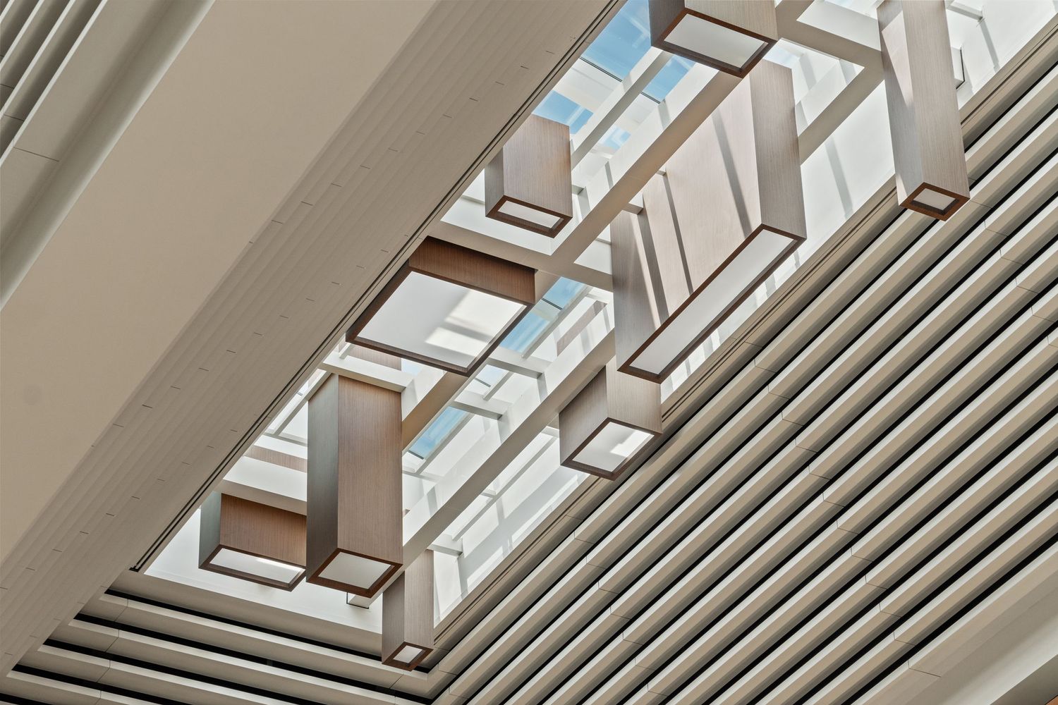 Contemporary architectural ceiling design with geometric skylights and linear metal beams.