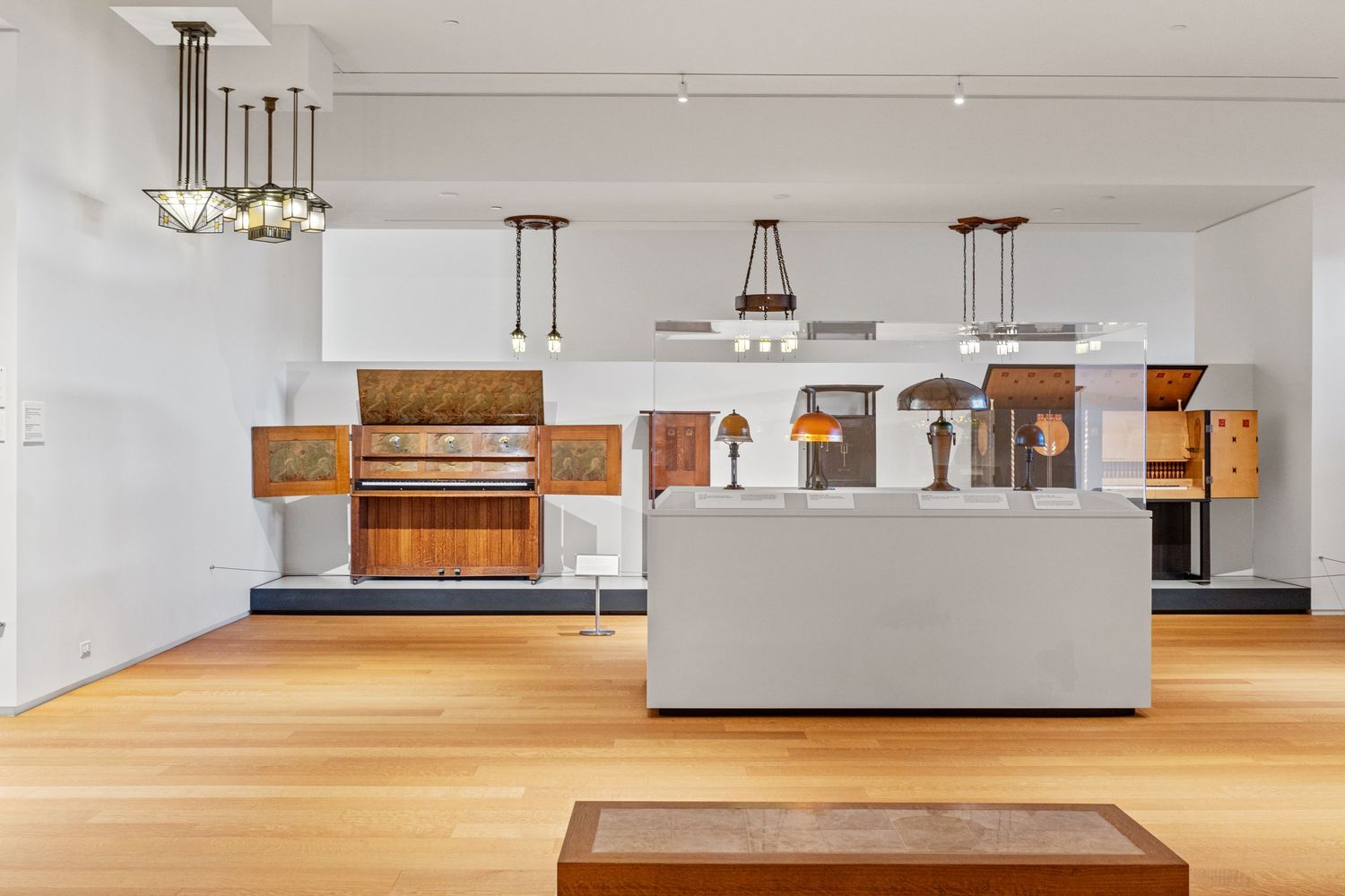 Modern museum gallery interior with hardwood floors and display cases showcasing artifacts and artwork.