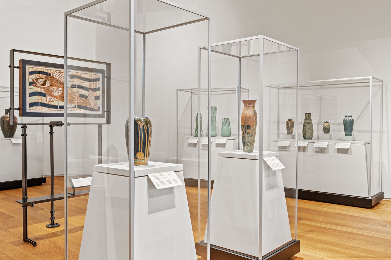 Clean white museum space with glass display cases arranged in a minimalist exhibition layout.