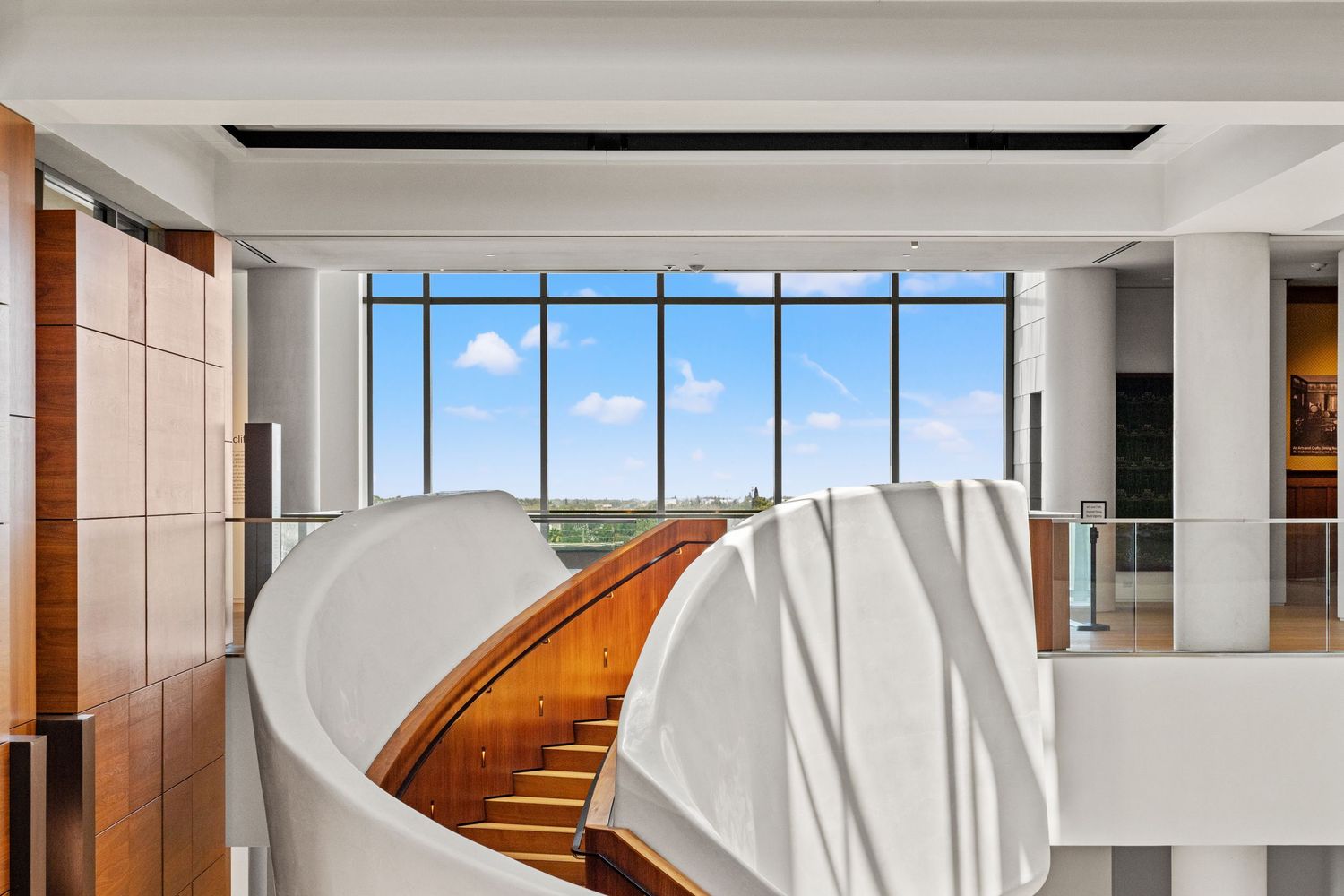 Bright museum hallway with floor-to-ceiling windows and wooden accents.
