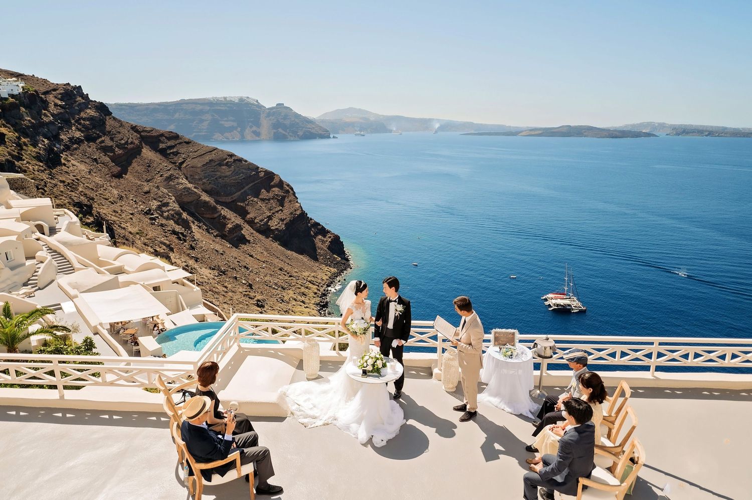 Wedding ceremony setup on a cliff-side terrace with stunning ocean views in Santorini.