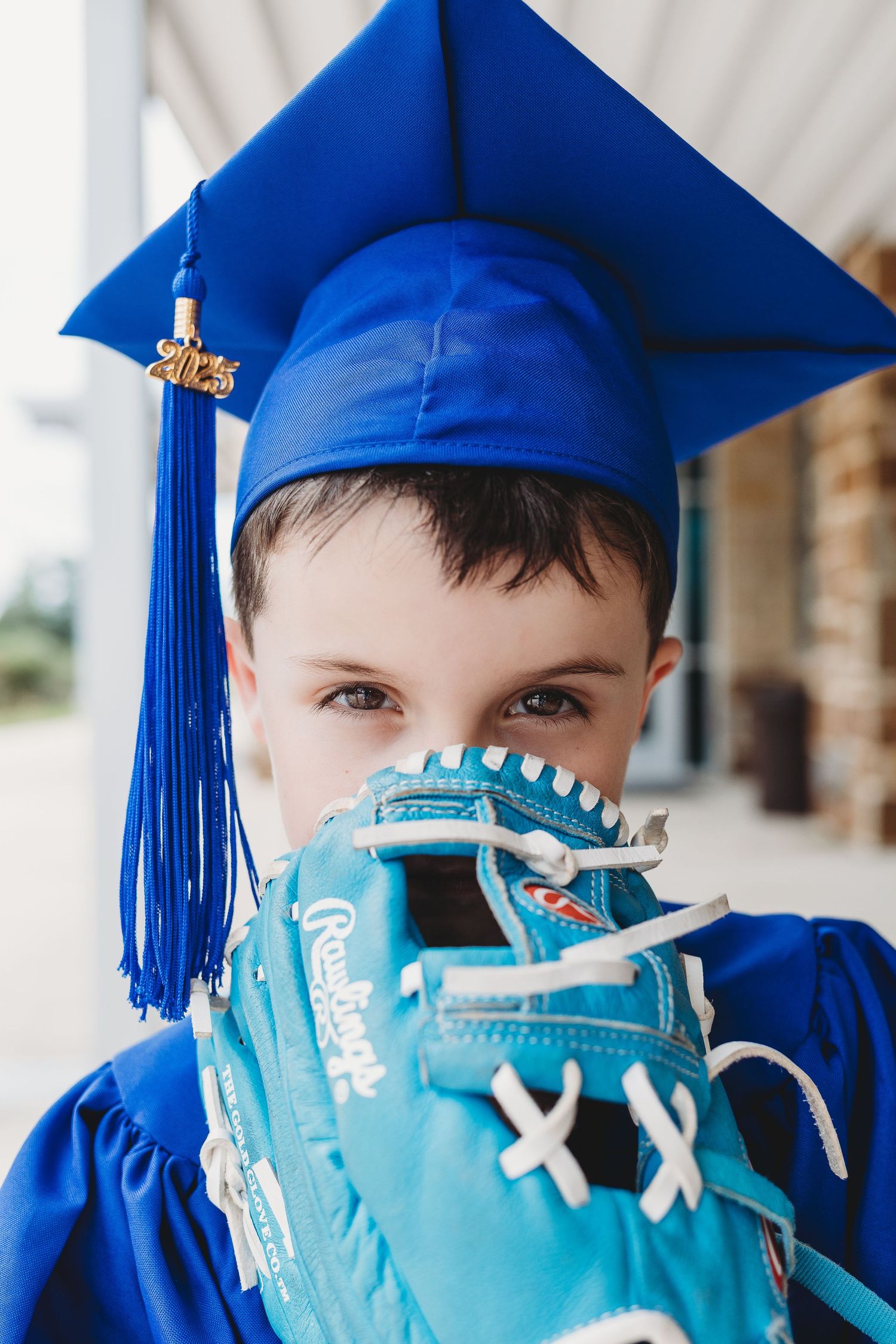 Two children in red graduation caps and gowns viewed from behind in field.