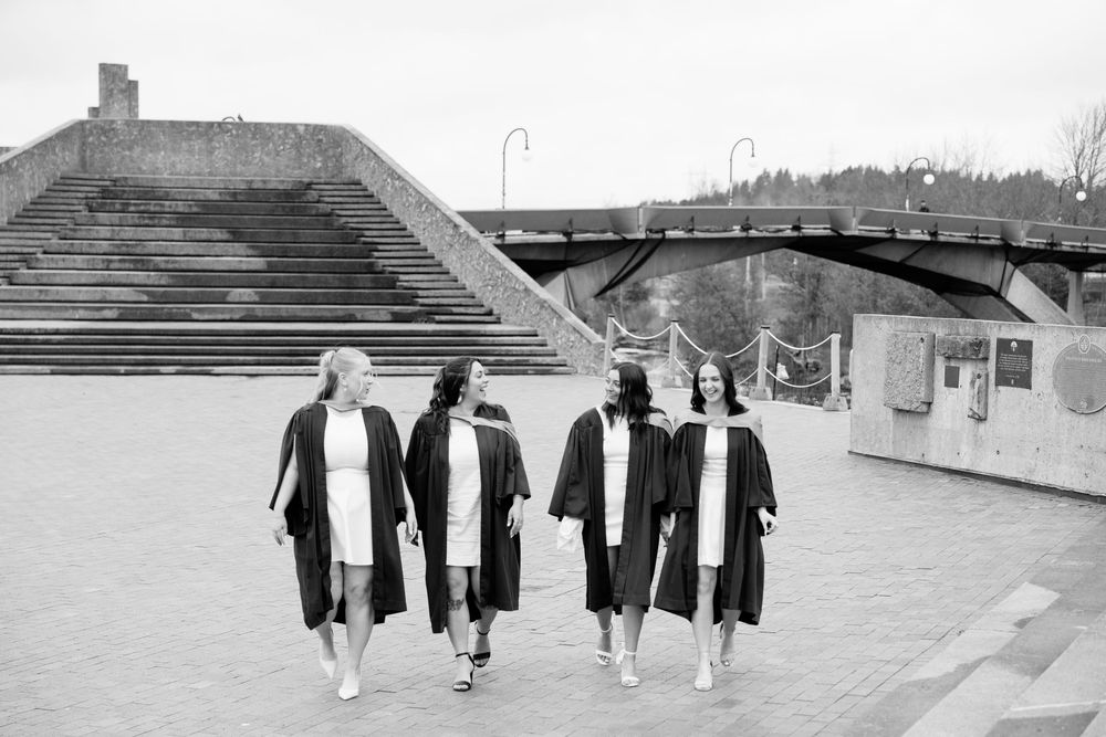 Graduates in black robes walk together outdoors in a vintage black and white photograph.