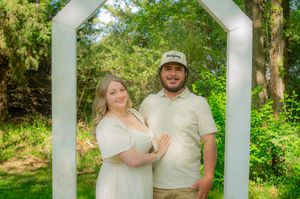 Family portrait taken outdoors with white pillars and lush greenery in the background.