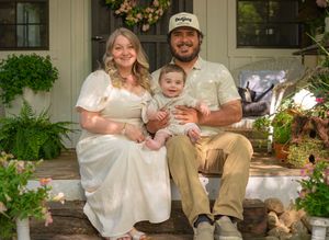 Family portrait on a charming country porch with potted plants and vintage details.