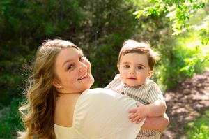 Candid family moment captured in a sunlit garden setting with natural greenery.