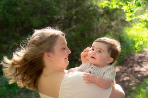 Sunlit outdoor portrait session showing tender family interactions against lush greenery.
