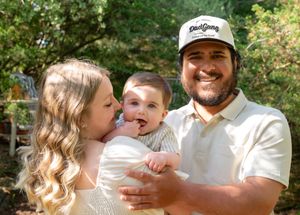 Family sitting together outdoors in casual attire sharing a joyful moment.