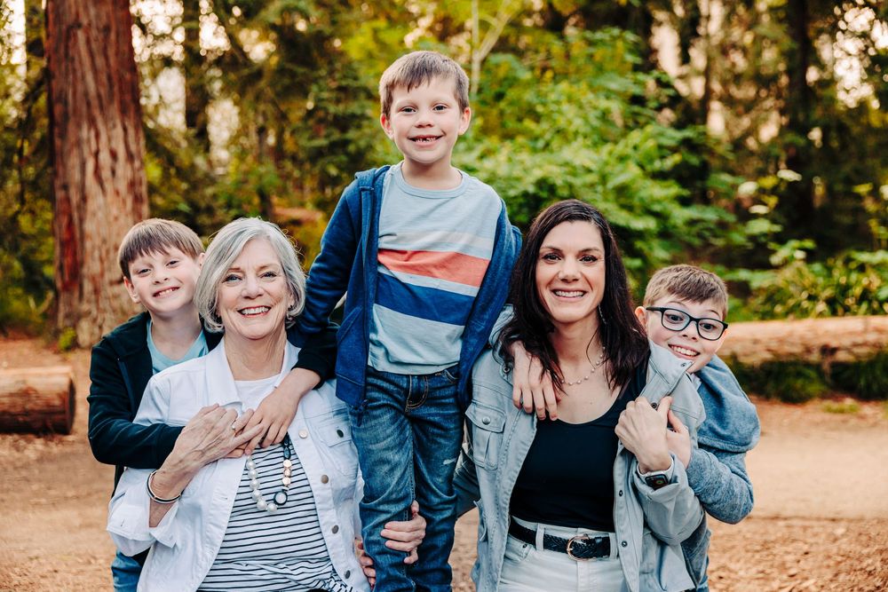Family enjoying playful candid moments together in an autumn forest setting with fallen leaves.