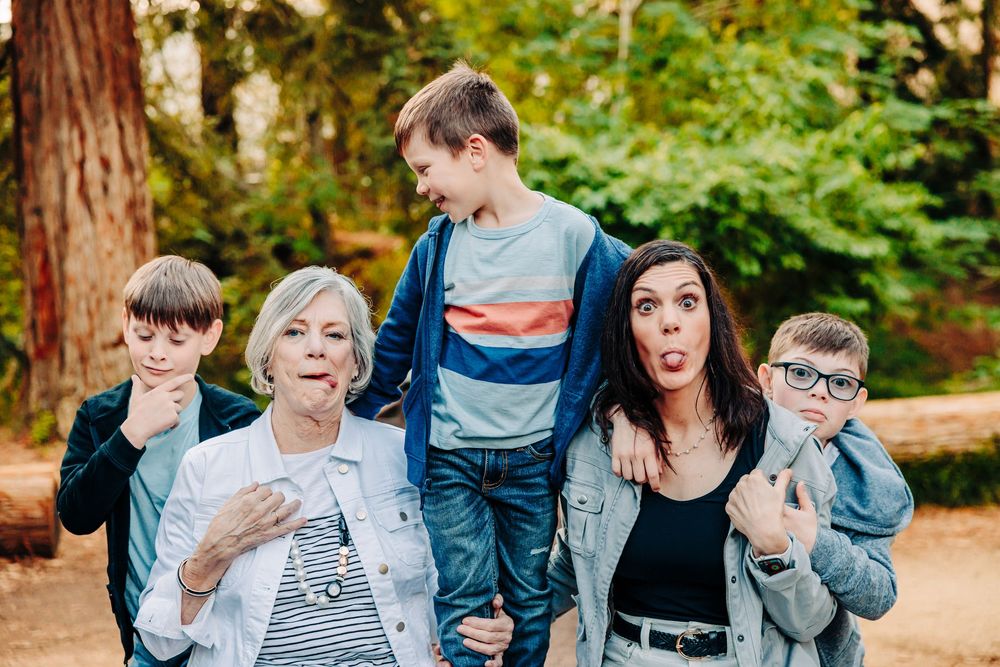 Family group poses casually outdoors against a backdrop of tall trees and natural greenery.