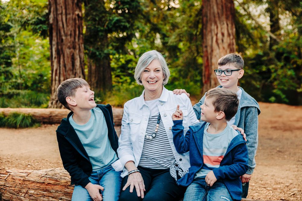 A joyful family shares candid moments together while sitting on fallen logs in an autumn forest setting.