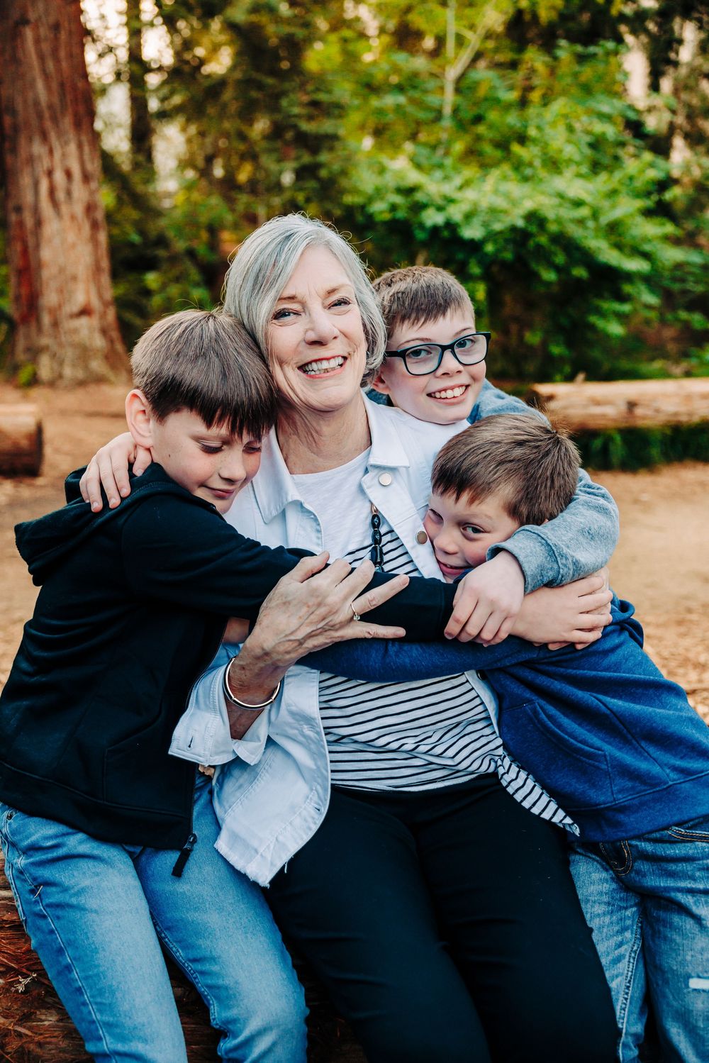 A playful family photoshoot sequence showing joyful embraces and laughter in a wooded outdoor setting.